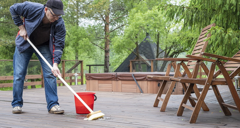 Caucasian man cleans a wooden deck