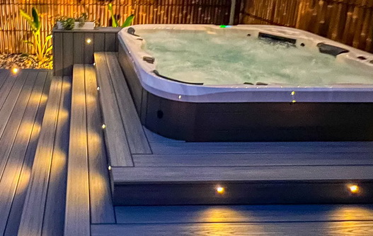 Outdoor deck with hot tub with floor lighting at night